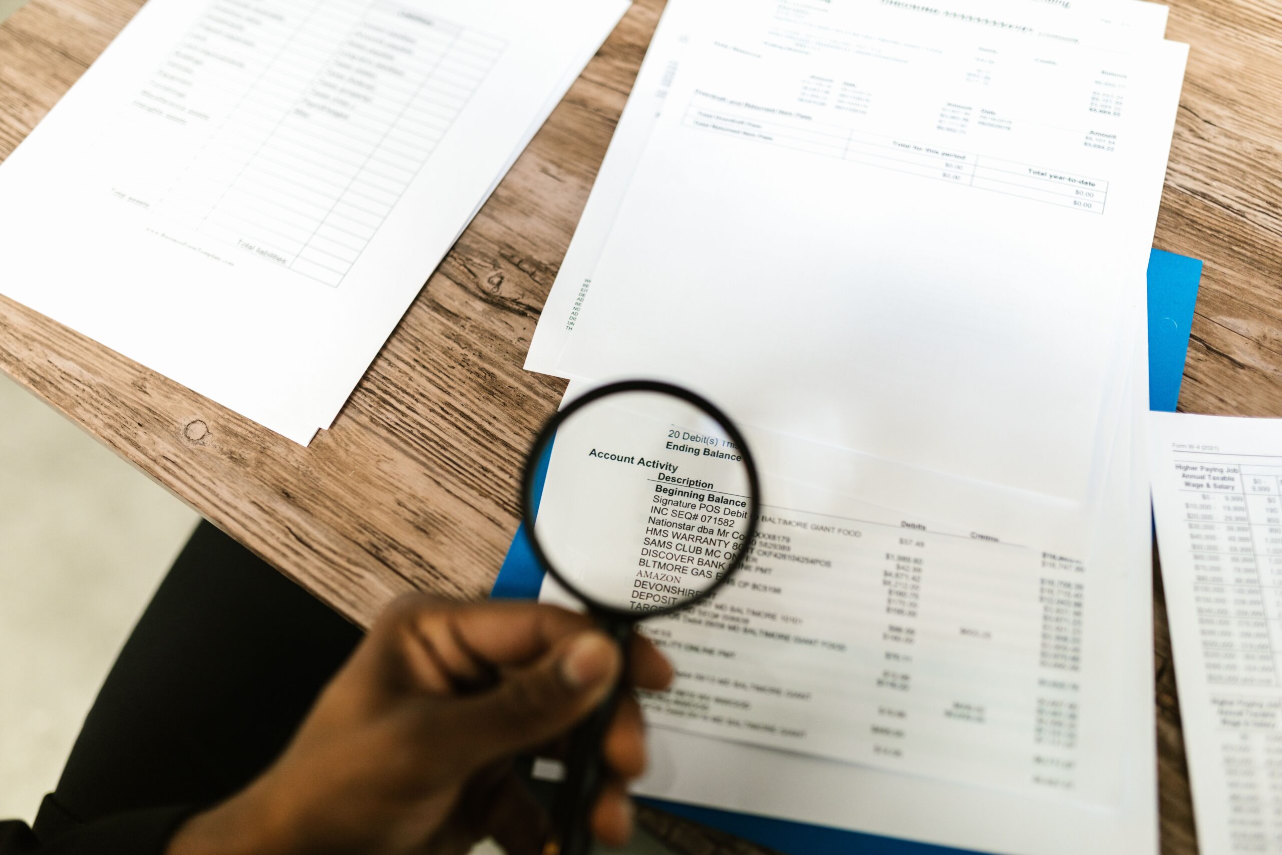 Consultant réalisant un audit documentaire avec loupe sur des documents de gestion